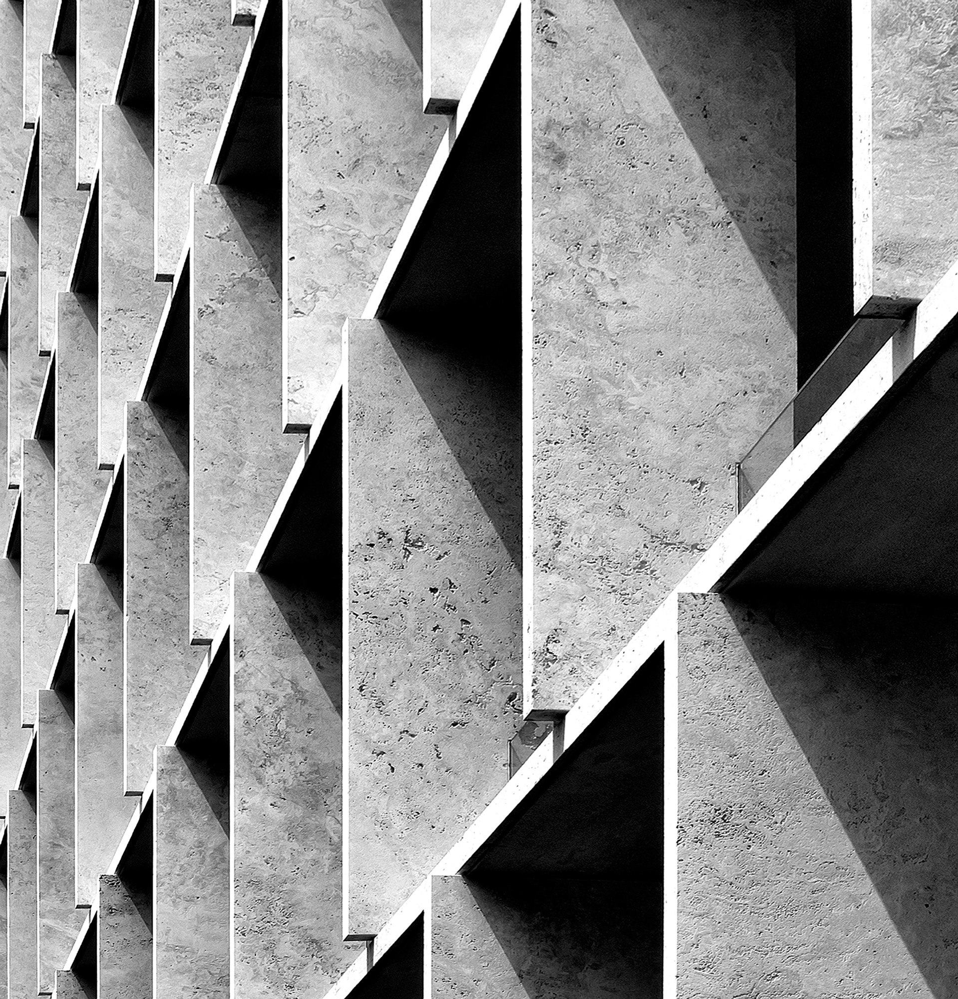 A concrete facade in raking light, its structure repeating across the frame.